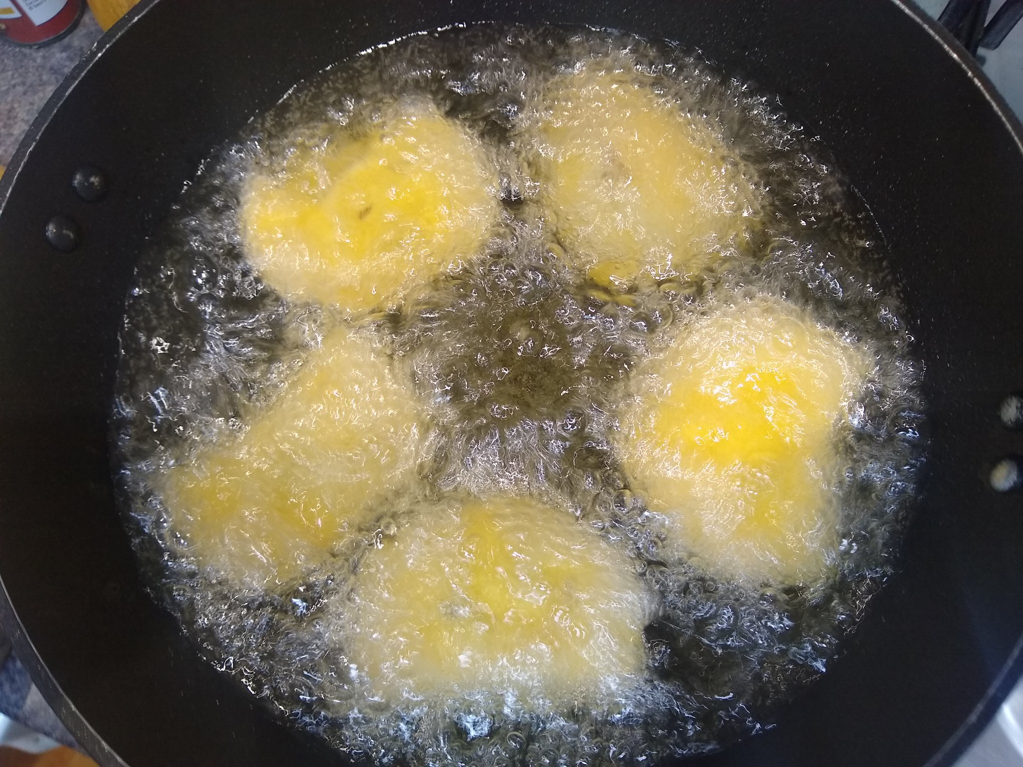 Picture of 5 deep frying empanadas in hot bubbling oil.